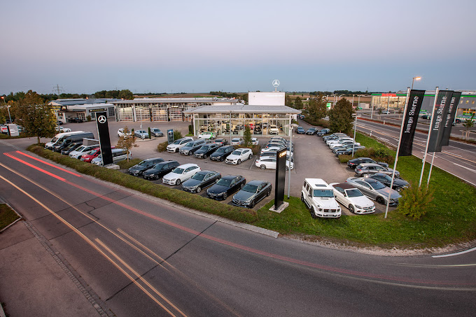 Ein Autohaus an einer Straßenkreuzung aus der Vogelperspektive. Auf dem Gelände sind viele PKW ausgestellt.