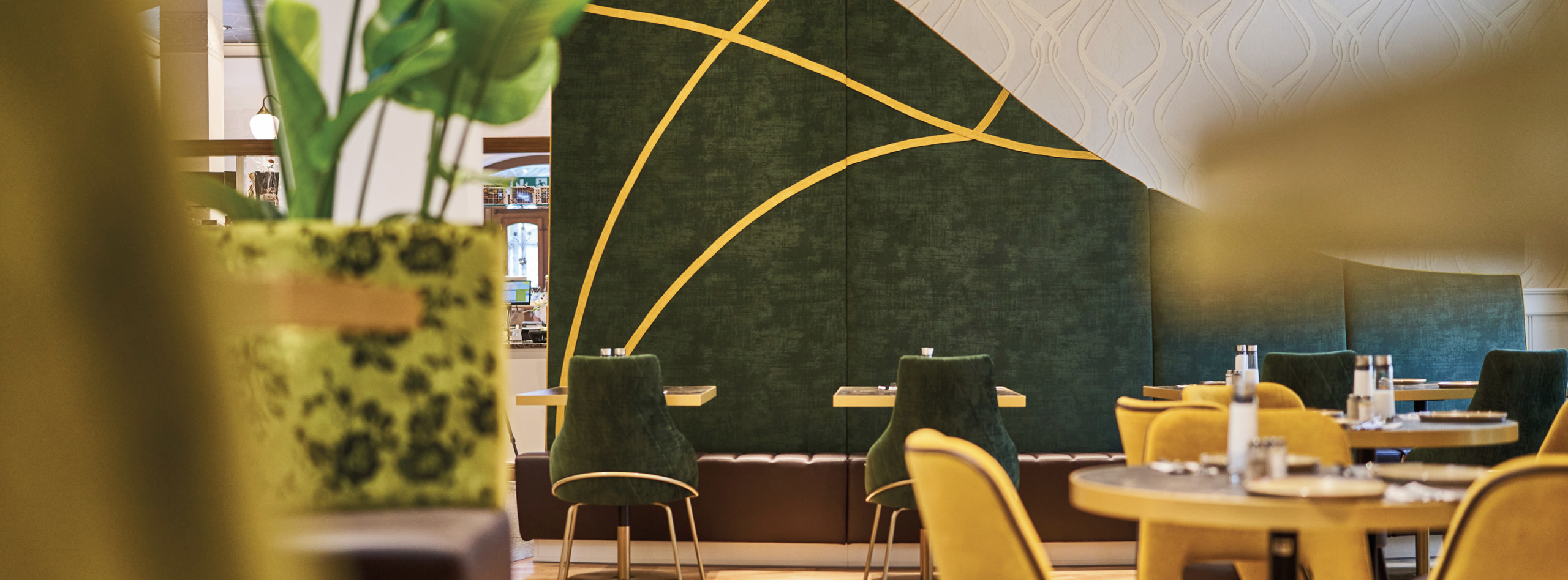 Sitzgruppen mit grünen Samtstühlen vor dunkelgrüner Wand.