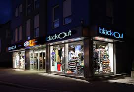 Außenaufnahme bei Nacht von einem Geschäft mit beleuchteten Schaufenstern. In den Schaufenster erkennt man Skateboards, Mode, Rucksäcke und weiteren Sportbedarf.