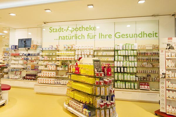 Innenraum einer Apotheke mit gelbem Boden und vollen Regalen und Ausstellern.
