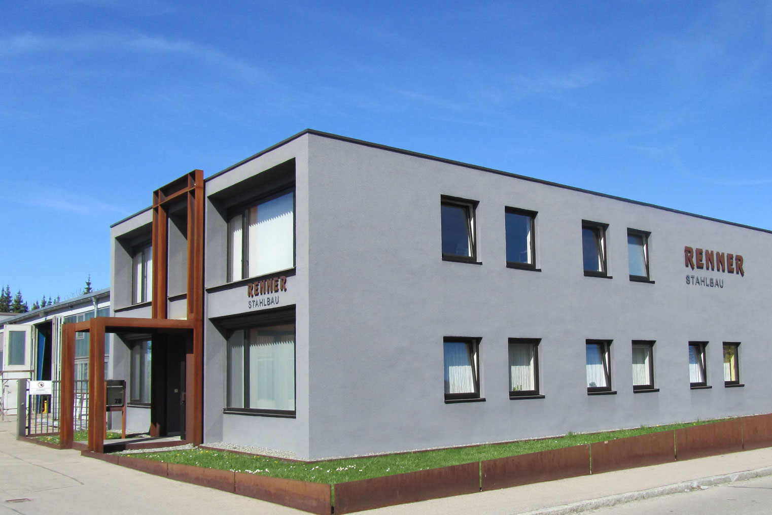 Modernes Graues Flachdachgebäude mit rostiger Stahlkonstruktion im Eingangsbereich